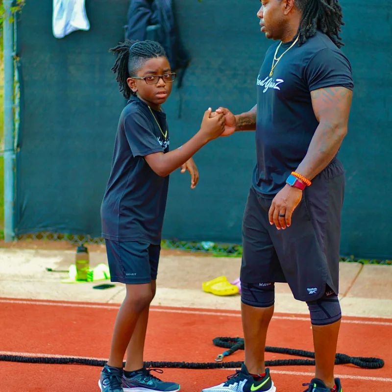 Posh Rock coach and a young player sharing a handshake on the court after a training session