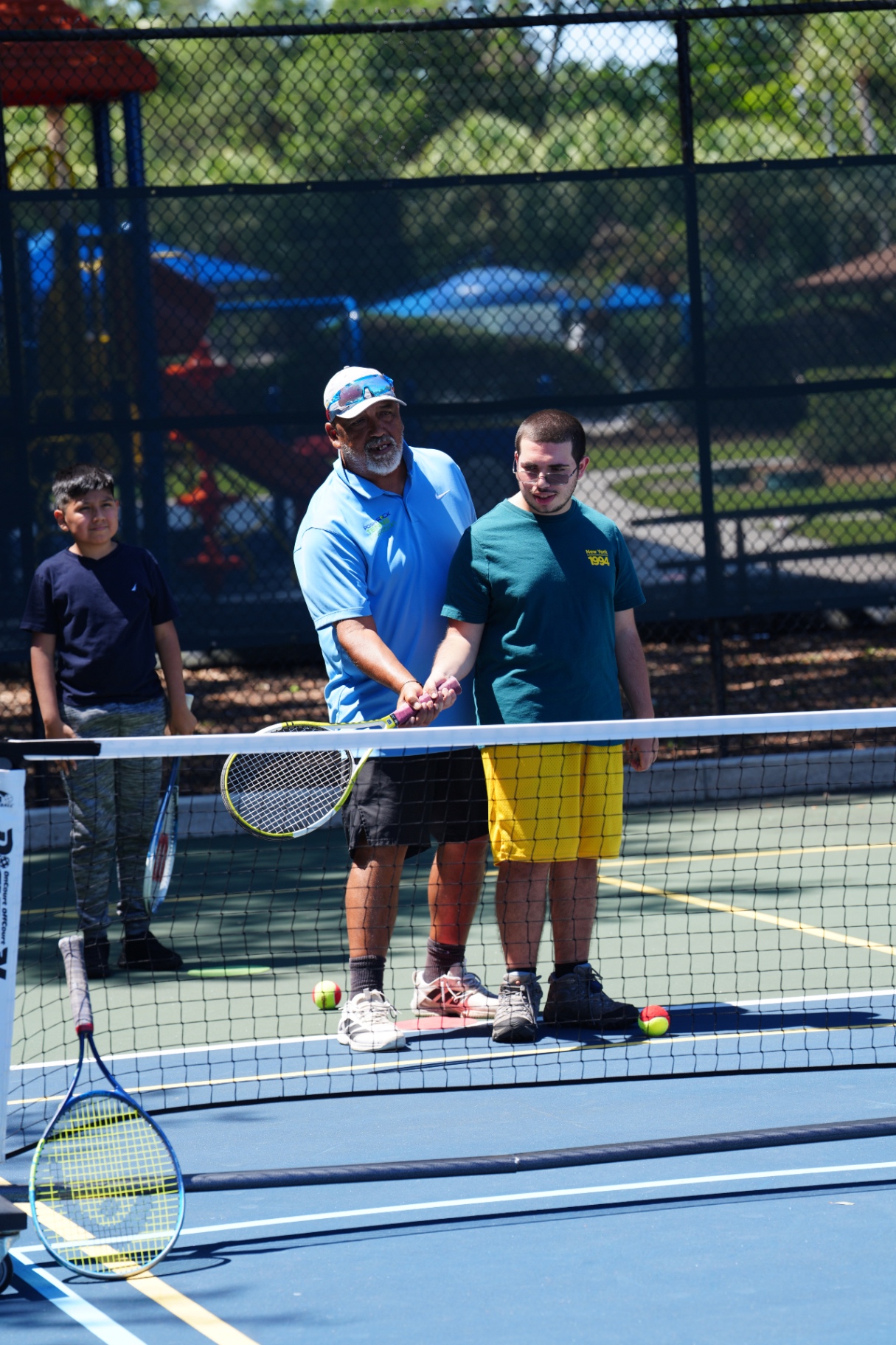 Posh Rock coach guiding a young player's forehand grip at the net during a clinic